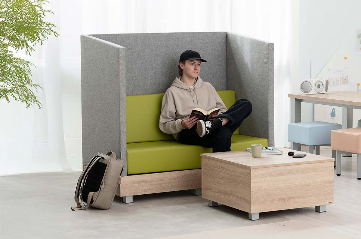 Chillo Schallschutzsofa Chillo Schallschutzsofa mit Chillo Couchtisch und jungem Mann in Lehrerzimmer-Setting