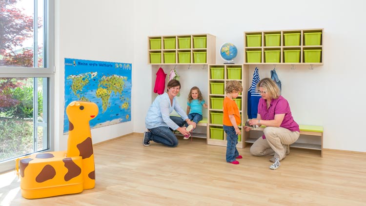 Erzeiherinnen helfen Kindern beim Anziehen der Schuhe