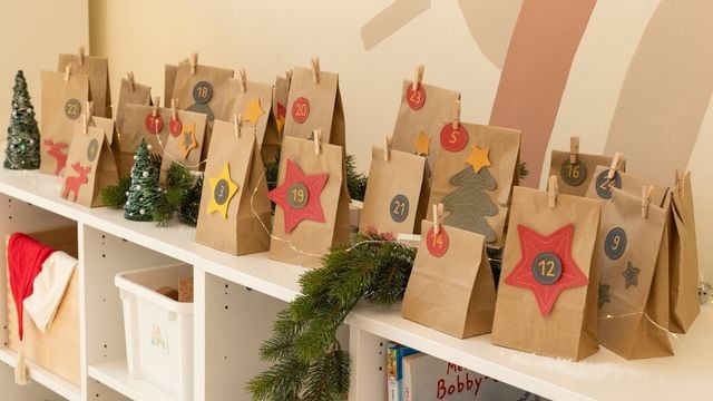 Braune Adventstüten mit Sternen verziert sind auf einer Kommode aufgereiht