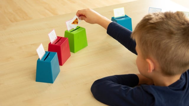 Kinder sitzt am Tisch und spielt mit Becherquizzer
