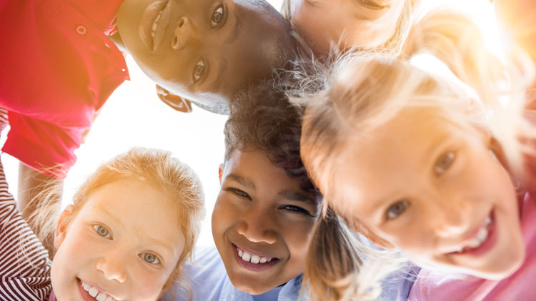 Kinder stehen im Kreis und lachen in Kamera