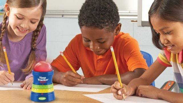 Drei Kinder sitzen am Tisch und schreiben