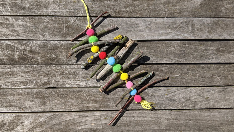 Pompons und Äste zu einem Windspiel verbastelt.