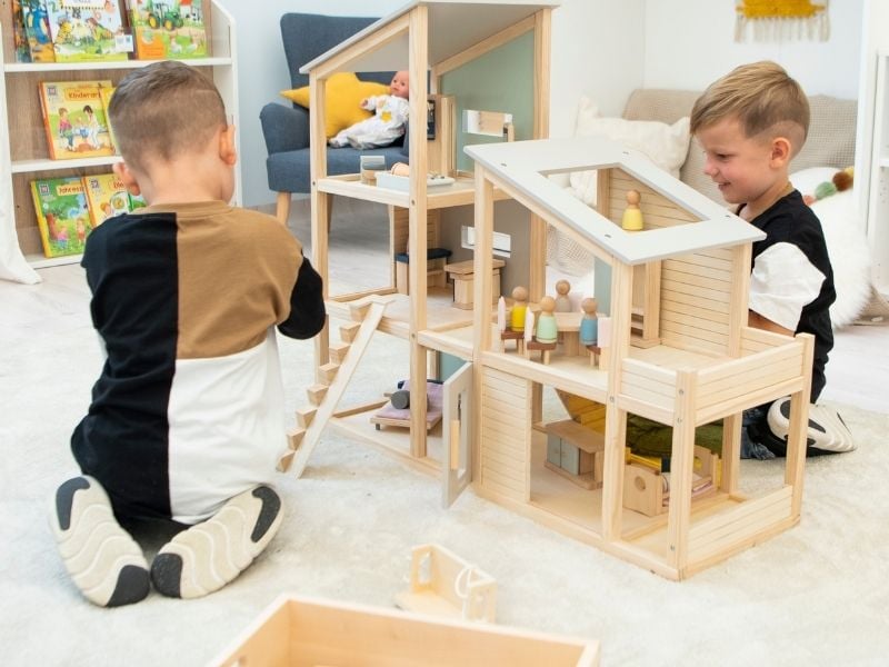 Zwei Jungen sitzen auf dem Boden und spielen mit einem Spielhaus