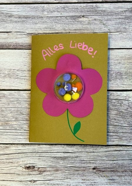 Grusskarte mit einer Blume auf der Front, die mit einer gefüllten Acrylglaskugel verziert ist.