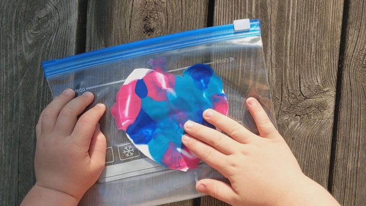 Farbe mit den Fingern in einem Plastikbeutel verteilen, ist eine schmutzfreie Maltechnik.