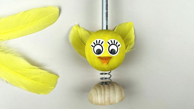 Wackelfigur Küken Ein gebasteltes Küken das auf einem Holzstück mit einer Spiralfeder platziert ist