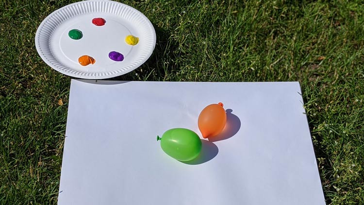 Fingerfarben von betzold.de werden mit einem Luftballon auf Papier vermalt.
