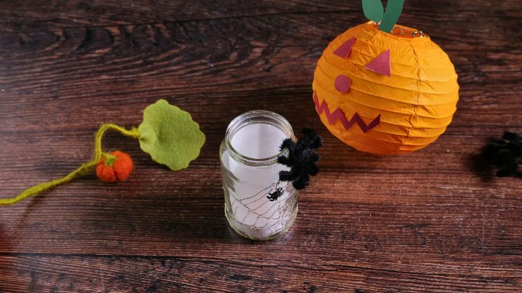 Mit einem Windlicht aus Glas, Bastelkleber und weissem Transparentpapier entsteht ganz einfach ein Halloween-Windlicht mit Spinnennetz.
