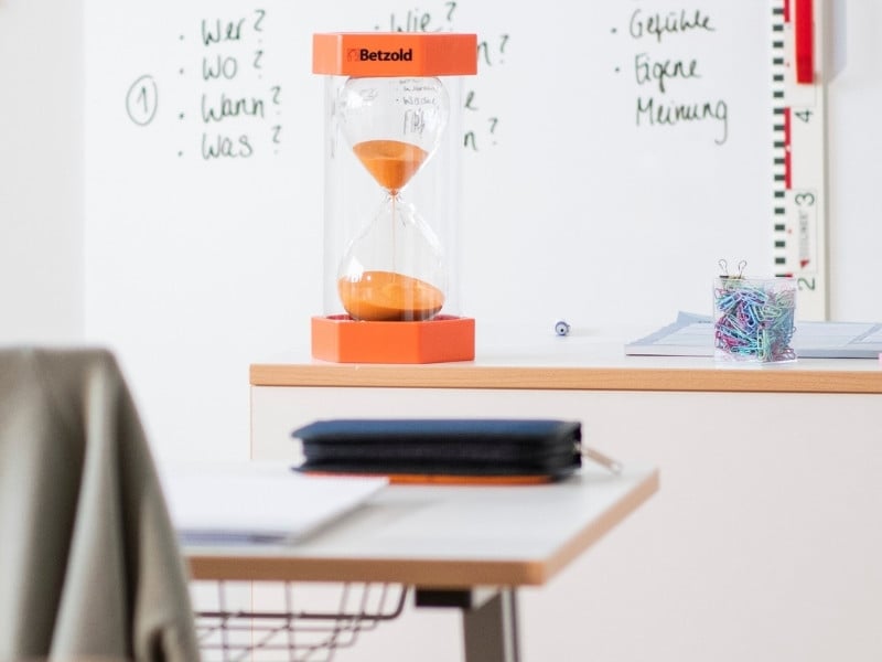 Konzentration Sanduhr grosse orangene Sanduhr steht auf dem Lehrerpult