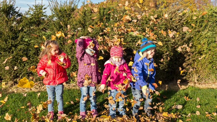 Kinder spielen im Herbstlaub