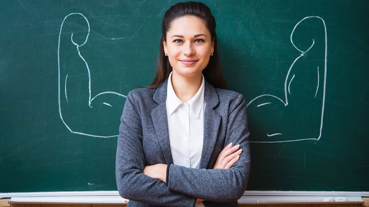 Lehrerin vor Tafel mit aufgemalten starken Armen