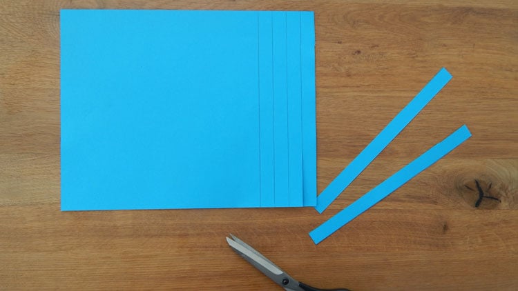 Blaues Papier wird in Streifen geschnitten